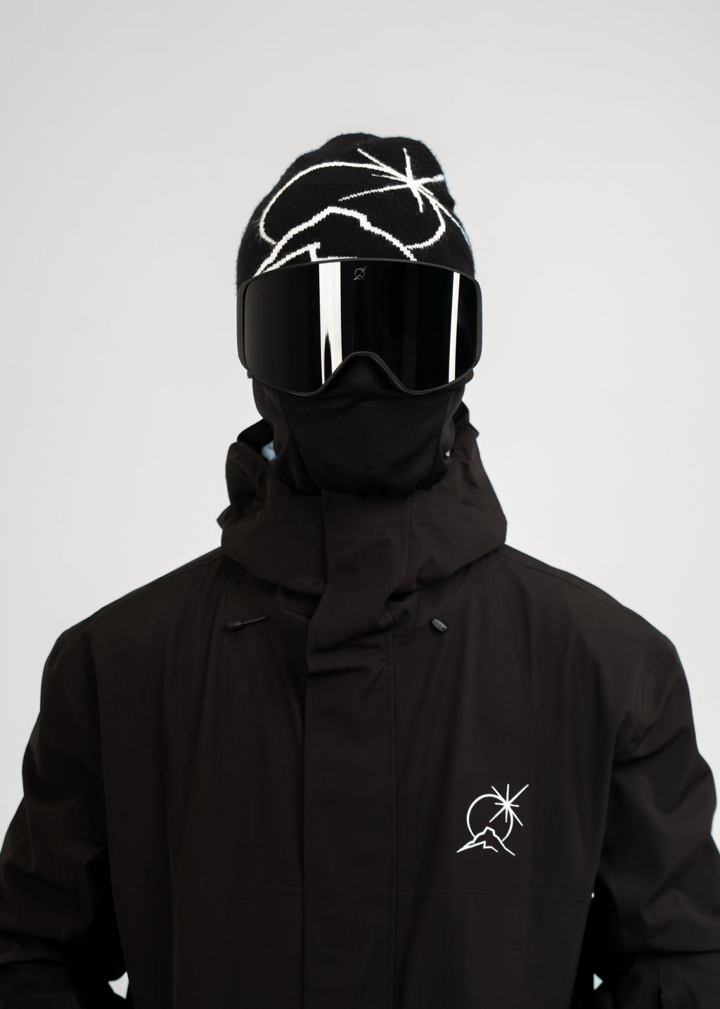 Person wearing a black Polar Pursuit beanie with reflective visor and black Polar Pursuit jacket on a white background