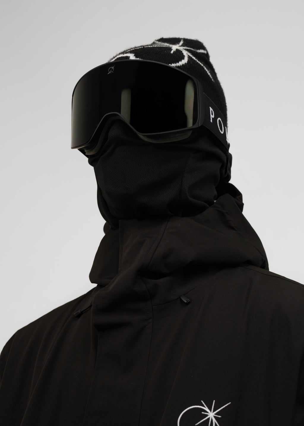 Person wearing a black Polar Pursuit hooded jacket with a logo Polar Pursuit on a gray background