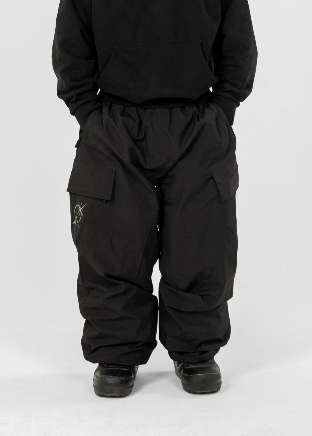 Person wearing a black Polar Pursuit  snowsuit and Polar Pursuit hat on a white background