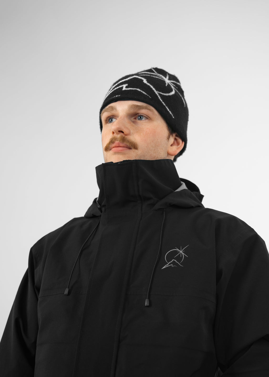 Person wearing a black Polar Pursuit jacket and Polar Pursuit beanie with a logo on a white background
