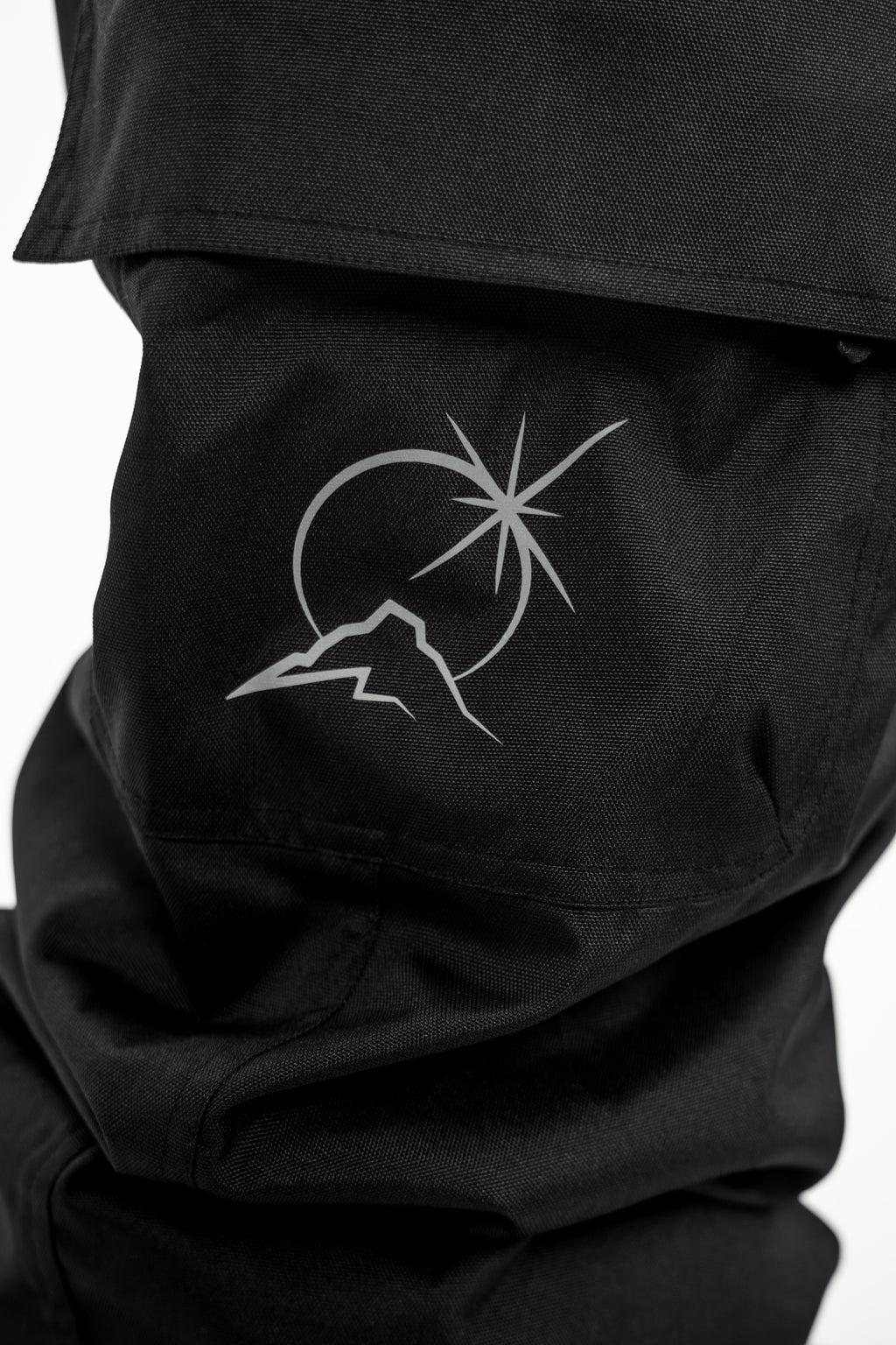 Black Polar Pursuit snowpants with a mountain and star design on a white background