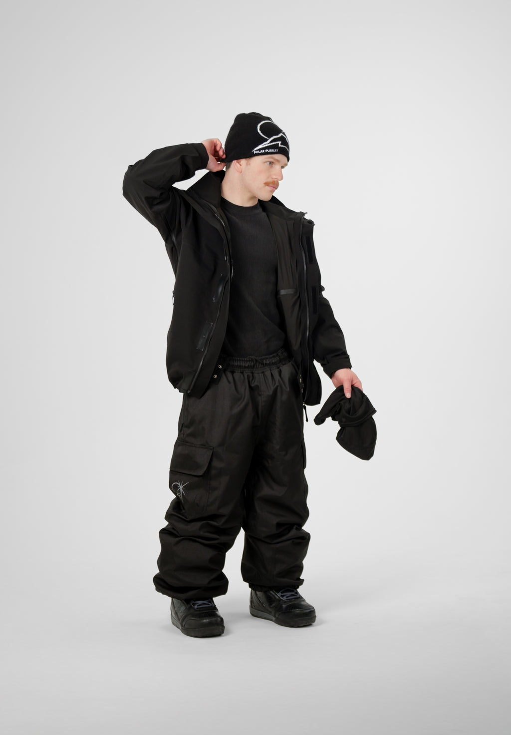 Person wearing a black Polar Pursuit outfit with a Polar Pursuit jacket, Polar Pursuit pants ,and a Polar Pursuit beanie on a white background
