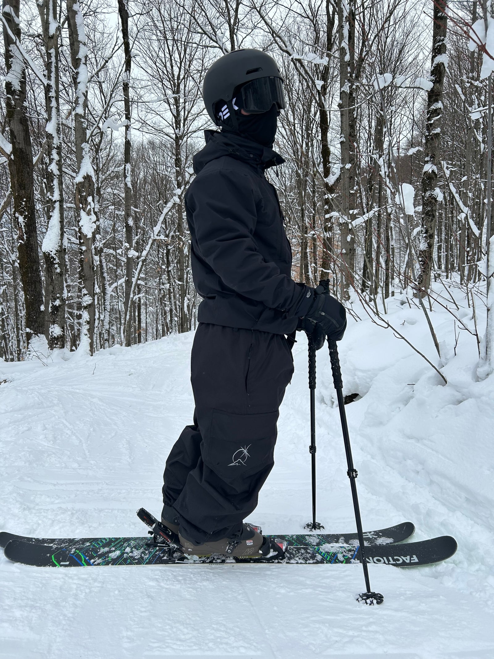 Person skiing with skis and poles on a snowy forest path with Polar Pursuit soft fabric baggy snow pants frostline.