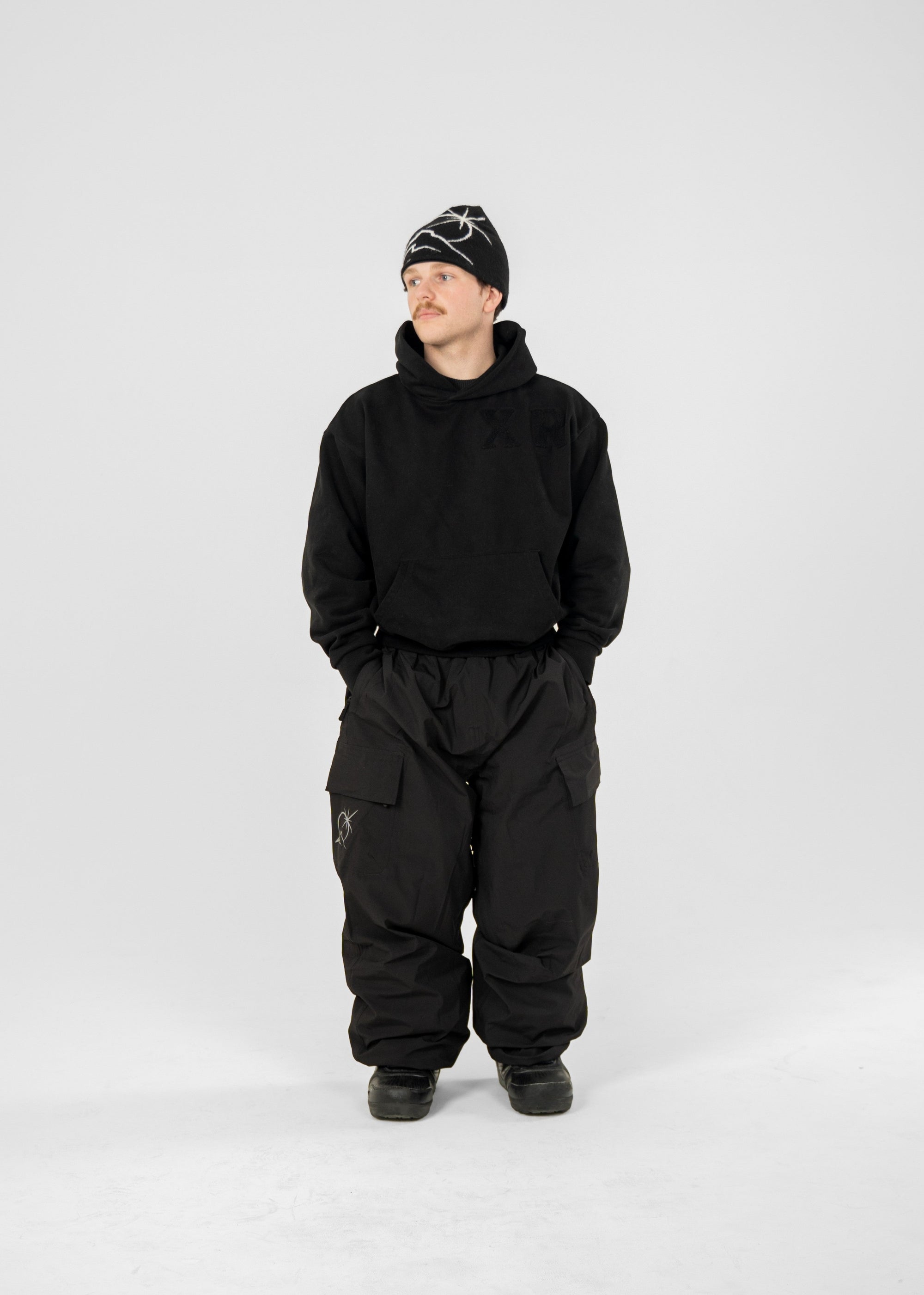 Person wearing a black Polar Pursuit  snowsuit and Polar Pursuit hat on a white background (Tom is 160cm 68kg wearing size M)